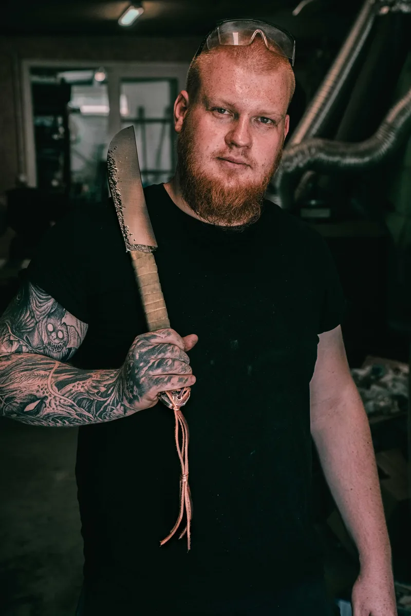 Jakub Wojsa w warsztacie z ręcznie wykonanym nożem typu chopper
